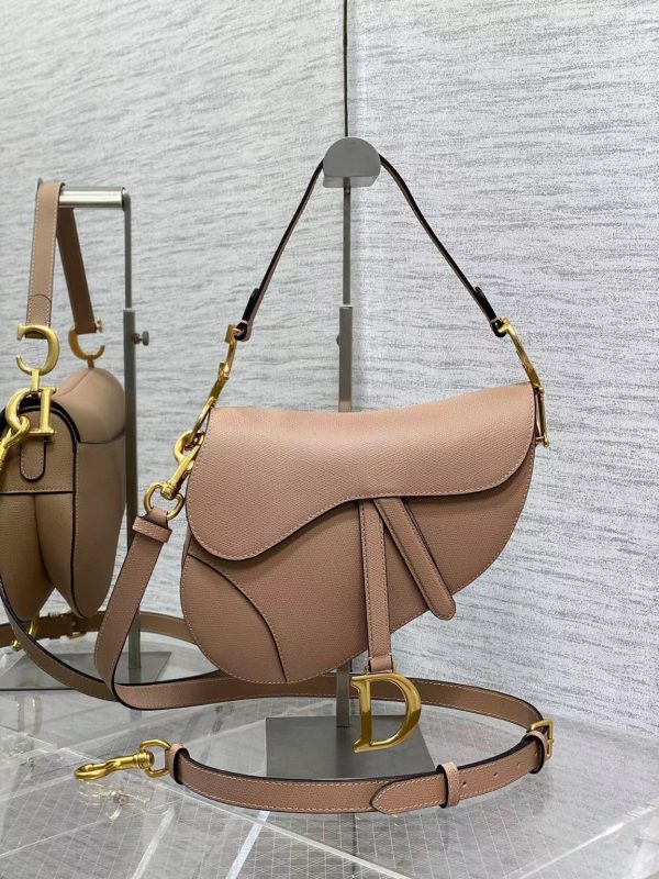 DIOR Saddle Bag With Strap. Original Quality Bag including gift box, care book, dust bag, authenticity card. Maria Grazia Chiuri brings a fresh update to the iconic Saddle bag. Crafted in grained calfskin, the legendary design features a Saddle flap with a magnetic 'D' stirrup clasp, as well as an antique gold-finish metal 'CD' signature on either side of the strap. Featuring a thin, adjustable and removable shoulder strap, the Saddle bag may be carried by hand, worn over the shoulder or crossbody.