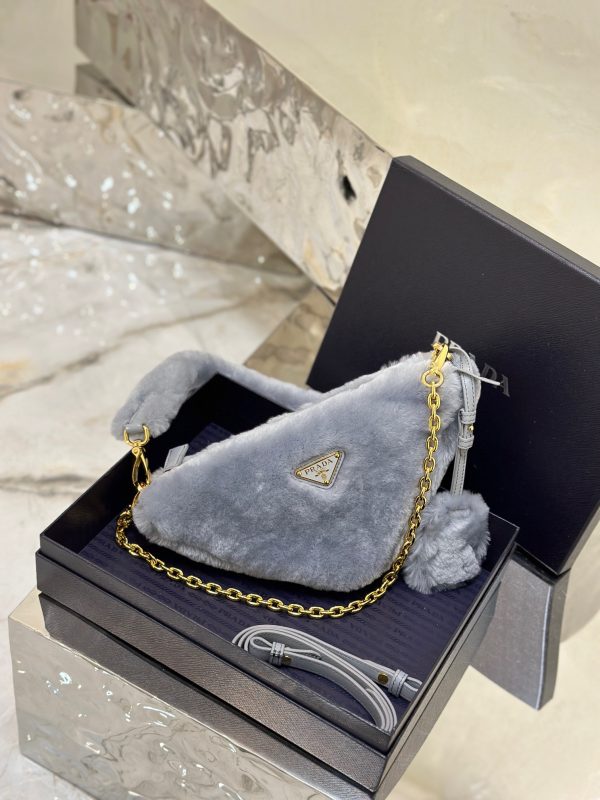 PRADA Shearling Mini Bag. Original Quality Bag including gift box, care book, dust bag, authenticity card. The softness and fuzziness of shearling accentuate the modern, wintry allure of this mini-bag characterized by its harmonious and delicate shape. The bag accented with a chain handle is decorated with the enameled metal triangle logo.