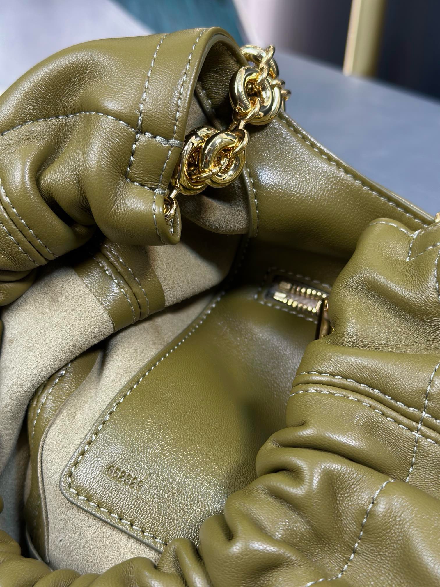 LOEWE Small Squeeze Bag: Where Elegance Meets Innovation in Luxurious Nappa Leather. The Squeeze bag embodies sophistication and femininity, crafted from luxurious nappa leather. It stands as a masterpiece, seamlessly blending traditional craftsmanship, innovative research, and distinctive design elements. The bag features a surprisingly lightweight ruched body, complemented by an adjustable donut chain and a tactile, squeezable handle. This particular version showcases the elegance of nappa lambskin in a compact size, adding an extra touch of refinement to its allure.