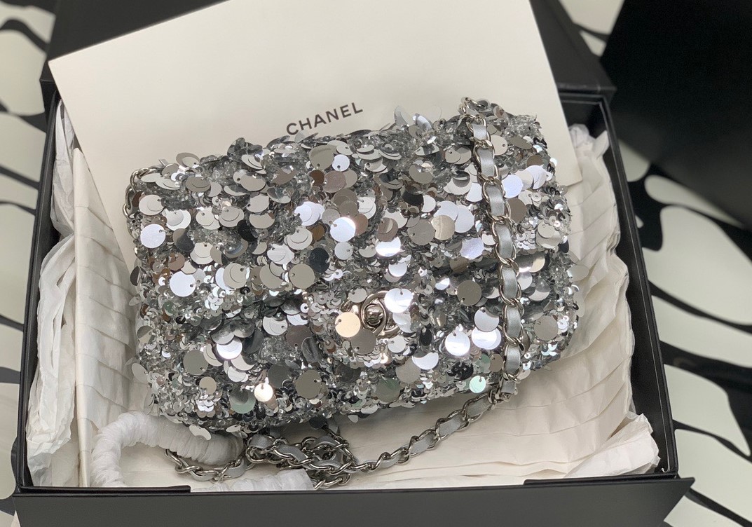 CHANEL Mini Flap Bag In Sequins. Original Quality Bag including gift box, care book, dust bag, authenticity card. This small sleek flap bag is beautifully crafted of the layering of small and large sequins that create the entire surface of the bag. The elegant handbag features polished chain link leather threaded shoulder straps and a Chanel CC turn lock. This opens to a leather interior with room for your necessities for day or evening with the timeless style.
