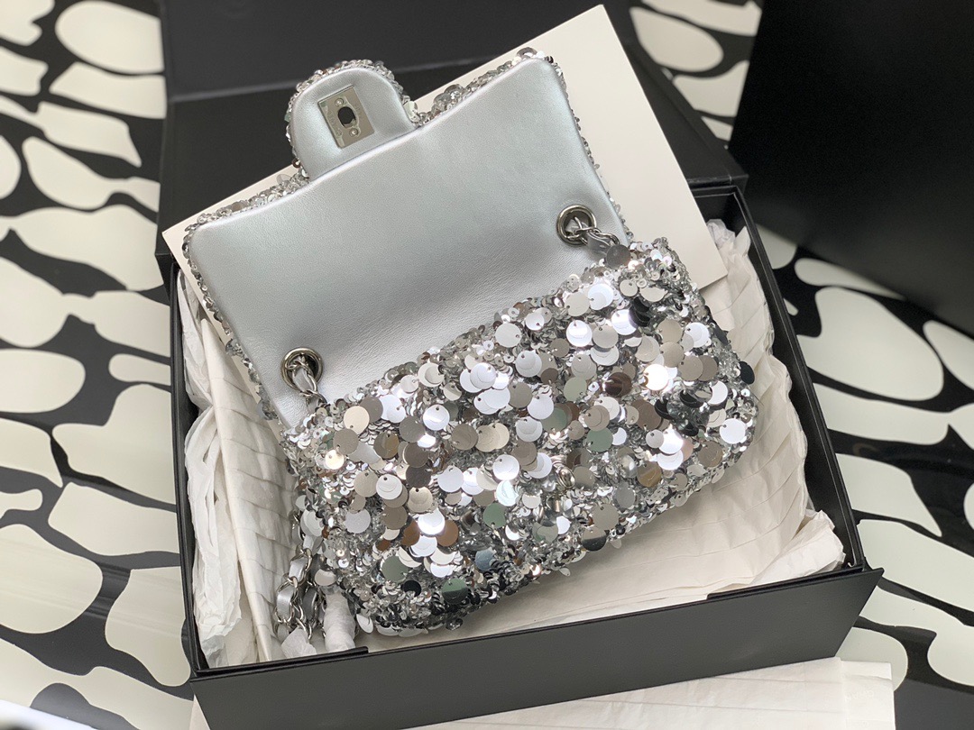 CHANEL Mini Flap Bag In Sequins. Original Quality Bag including gift box, care book, dust bag, authenticity card. This small sleek flap bag is beautifully crafted of the layering of small and large sequins that create the entire surface of the bag. The elegant handbag features polished chain link leather threaded shoulder straps and a Chanel CC turn lock. This opens to a leather interior with room for your necessities for day or evening with the timeless style.