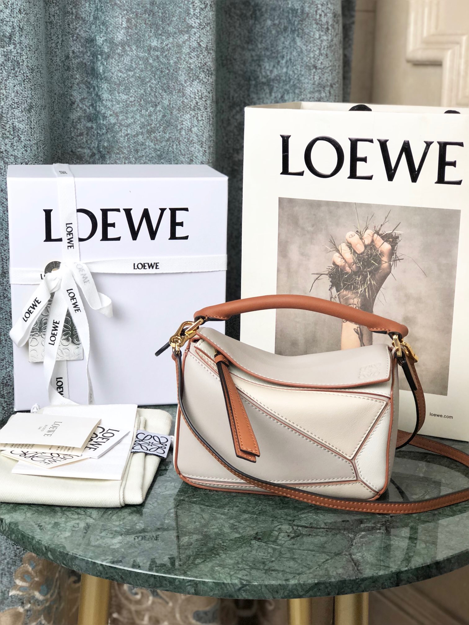 LOEWE Mini Puzzle Bag. Original Quality Bag including gift box, care book, dust bag, authenticity card. The Puzzle bag is the debut bag for LOEWE by Creative Director Jonathan Anderson. A cuboid shape and precise cutting technique create Puzzle’s distinctive geometric lines. This mini version is crafted in contrasting calfskins.