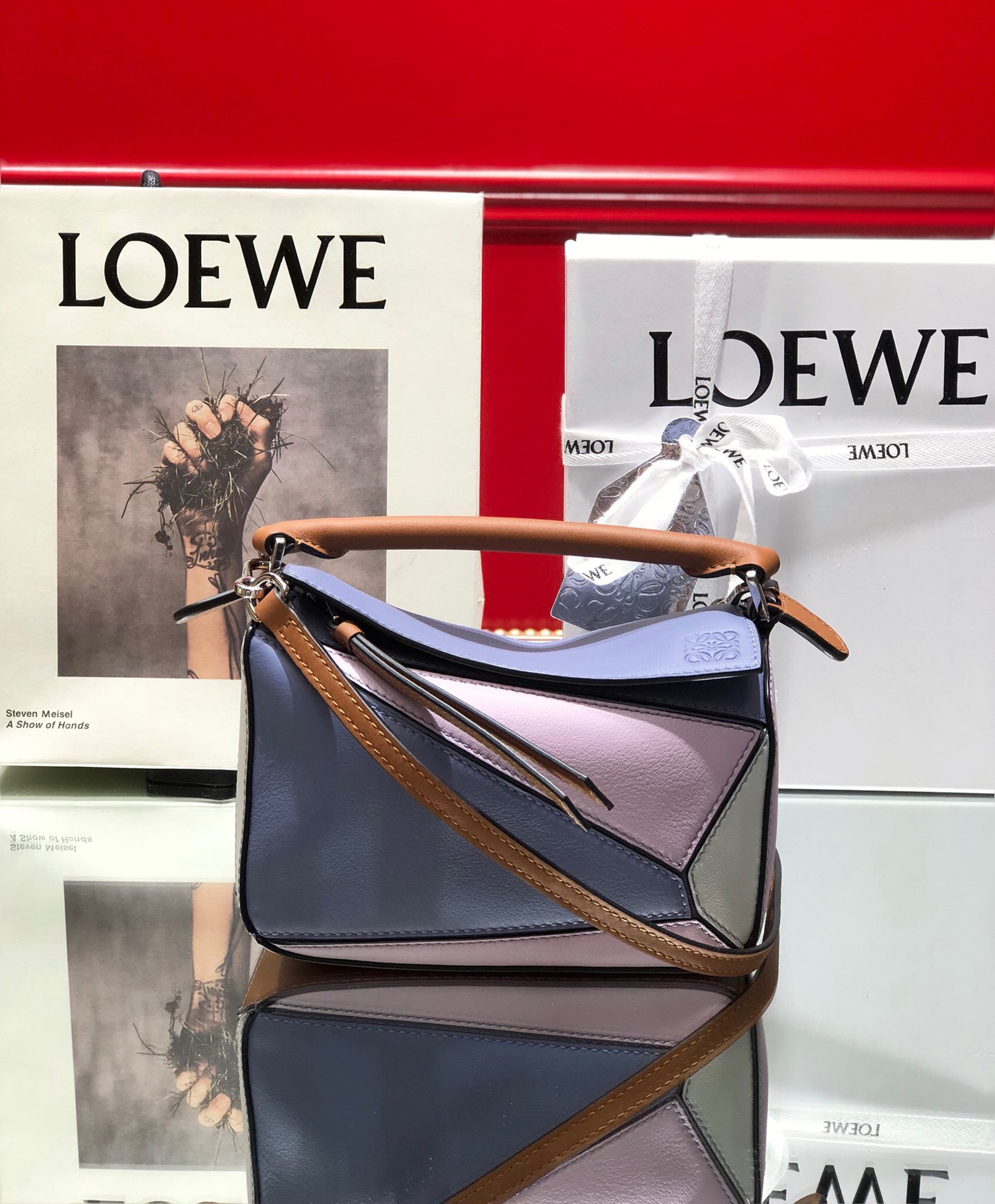 LOEWE Mini Puzzle Bag. Original Quality Bag including gift box, care book, dust bag, authenticity card. The Puzzle bag is the debut bag for LOEWE by Creative Director Jonathan Anderson. A cuboid shape and precise cutting technique create Puzzle’s distinctive geometric lines. This mini version is crafted in contrasting calfskins.