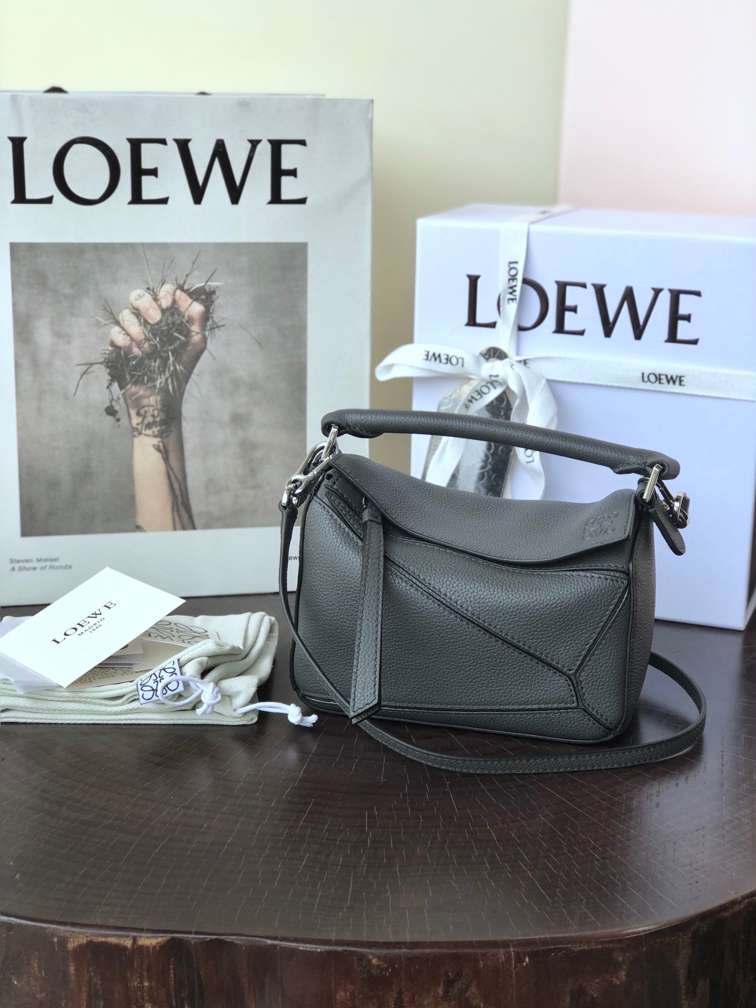 LOEWE Mini Puzzle Bag. Original Quality Bag including gift box, care book, dust bag, authenticity card. The Puzzle bag is the debut bag for LOEWE by Creative Director Jonathan Anderson. A cuboid shape and precise cutting technique create Puzzle’s distinctive geometric lines. This mini version is crafted in contrasting calfskins.