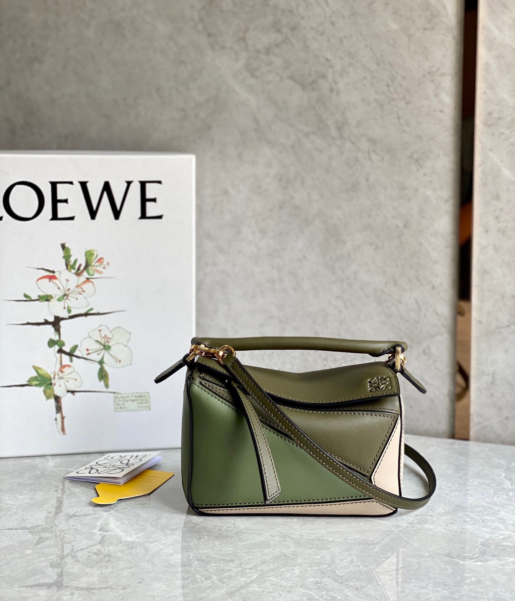 LOEWE Mini Puzzle Bag. Original Quality Bag including gift box, care book, dust bag, authenticity card. The Puzzle bag is the debut bag for LOEWE by Creative Director Jonathan Anderson. A cuboid shape and precise cutting technique create Puzzle’s distinctive geometric lines. This mini version is crafted in contrasting calfskins.