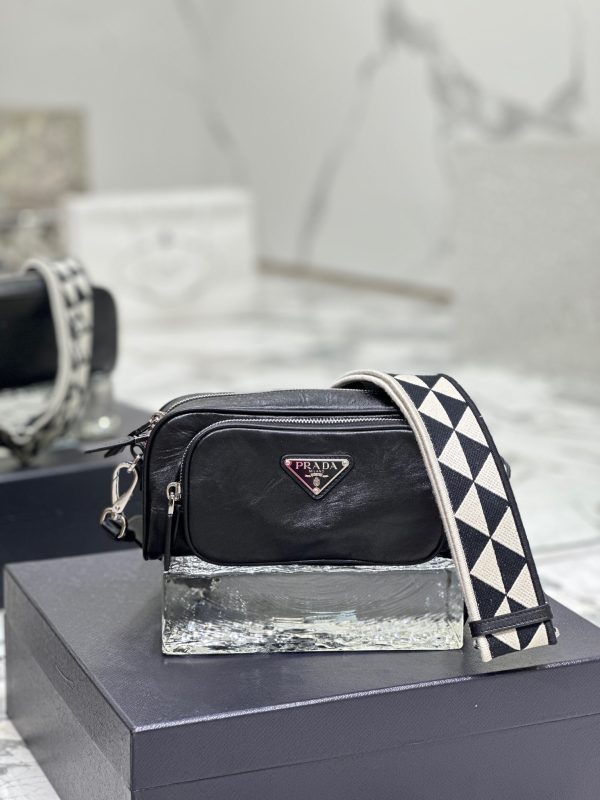PRADA Nappa Antique Leather Shoulder Bag. High-End Quality Bag including gift box, care book, dust bag, authenticity card. This bag with compact allure is made of nappa leather with a natural, glossy finish. The hand-made wrinkled effect contrasts with the constructed and rigid concept, reinterpreting an everyday object to be worn without constraints. Presented in the Spring Summer 2023 show, the style is accented with a finely embroidered shoulder strap with a sporty mood.