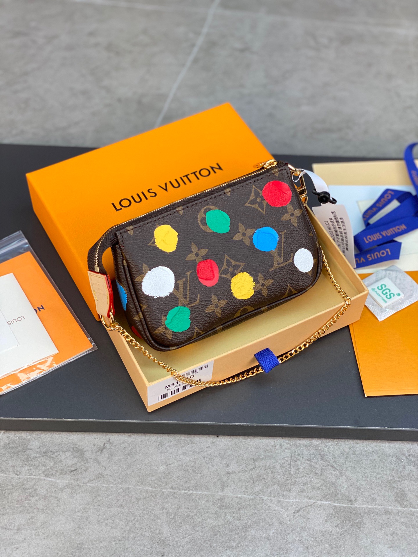 LOUIS VUITTON Mini Pochette Accessoires Pouch. High-End Quality Bag including gift box, care book, dust bag, authenticity card. This pochette is crafted of traditional damier checkered toile canvas in brown. The bag features a colorful depiction of house mascot Vivienne driving by the Eiffel Tower in Paris, and a polished brass chain link wristlet strap. The top zipper opens to a compact fabric interior. This is a chic and playful pochette, with luxury and style.