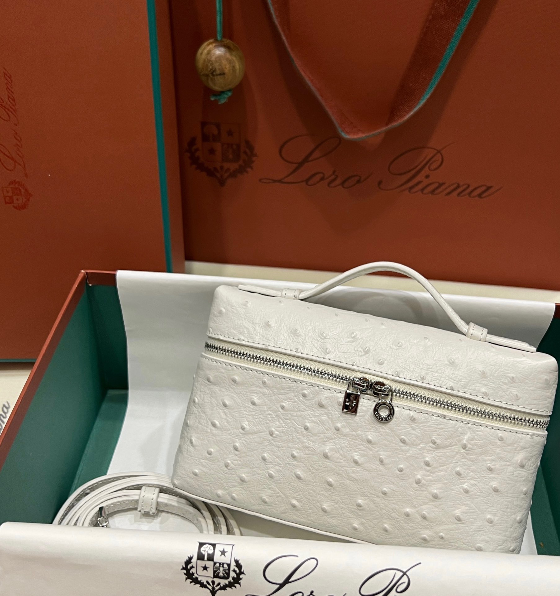 LORO PIANA Extra Pocket Pouch L 19. Elevate your essentials with exquisite luxury and timeless style. The Extra Pocket pouch is a perfect blend of opulent materials and a unique, minimalistic design. It caters to the needs of the contemporary, vibrant woman with its refined and practical layout. This adaptable accessory can function as a compact bag, offering convenience with its detachable shoulder strap and spacious opening. It allows you to effortlessly access all your essentials whenever needed. Meticulously crafted from sumptuous calfskin, its delicately hammered surface lends a captivating touch of luxury, boasting a naturally smooth texture and appearance.