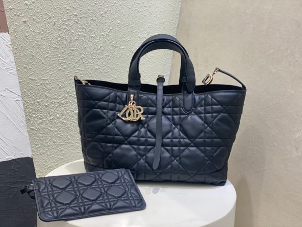 DIOR Toujours Bag: Elevate Everyday Elegance.  Unveiled during the Spring-Summer 2023 fashion show, the Dior Toujours bag effortlessly marries style and practicality. This exceptional piece, meticulously crafted from black calfskin adorned with striking Macrocannage topstitching, boasts a generously spacious interior compartment thoughtfully accompanied by a coordinating pouch, ensuring meticulous organization for all your essentials. The elegant leather strap closure not only provides security but also allows the iconic CD Lock closure to gracefully adjust the bag's sides, enhancing its timeless silhouette. With the convenience of adjustable leather handles and small notches, this petite masterpiece can be carried by hand with the utmost ease and sophistication.