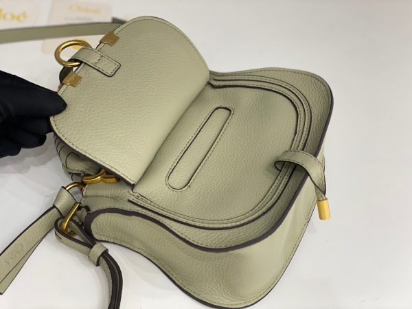 CHLOÉ Marcie Mini Double Carry Bag: Elegance in Miniature. Introducing a charming, petite rendition of the iconic Marcie handbag, this mini double carry bag exudes elegance with its meticulous craftsmanship in grained calfskin. Its clean, sleek lines and gracefully contoured design elevate the relaxed, slouchy silhouette, while the hand-wrapped leather handles impart an artisanal touch. The addition of metallic buckles bestows a polished and refined finish to this exquisite creation. Equipped with both double handles and a long, detachable shoulder strap, this mini bag epitomizes versatility, making it a must-have accessory for any occasion.
