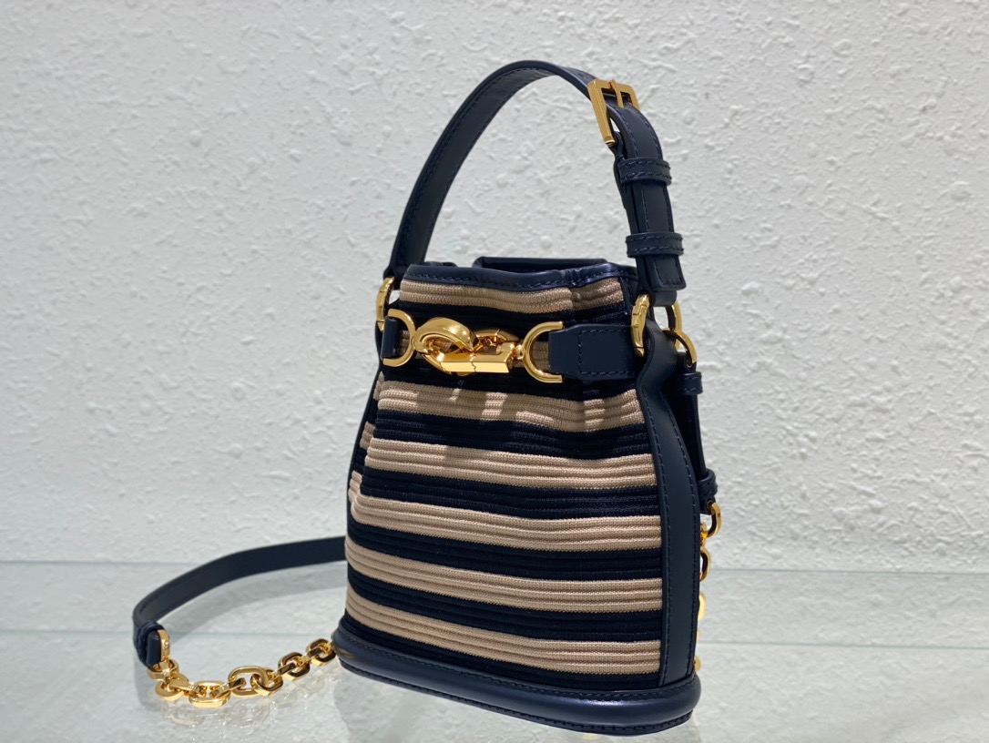 DIOR Small C'est Bag: Timeless Elegance, Effortless Style. Introducing the C'est Dior bag, a timeless and elegant creation for Fall 2023. Crafted in natural and denim blue raffia, it beautifully features the classic Marinière motif from ready-to-wear. Securing your essentials with a sophisticated CD Lock closure adorned with a twisting letter D, this bucket bag combines style with practicality. With a top handle and an adjustable, removable chain strap featuring a leather insert, this small-sized bag offers versatile carrying options—be it hand-held or comfortably draped over the shoulder.