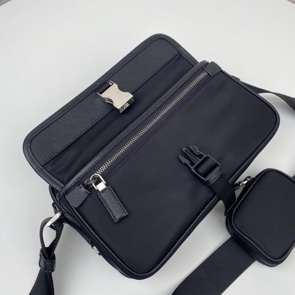 PRADA Nylon Cross-Body Bag. Original Quality Bag including gift box, care book, dust bag, authenticity card. This bag decorated with Saffiano leather trim presents compact volumes and a sleek design. With its distinctive side release buckle on the front, it comes with an easily adjustable shoulder strap. This cross-body bag featuring Saffiano leather trim with metal hardware and Prada logo lining, logo tag inside, enameled metal triangle logo outside. It has a main compartment with zipper, secondary compartment with flap and side release buckle, two front pockets, including one with zipper.