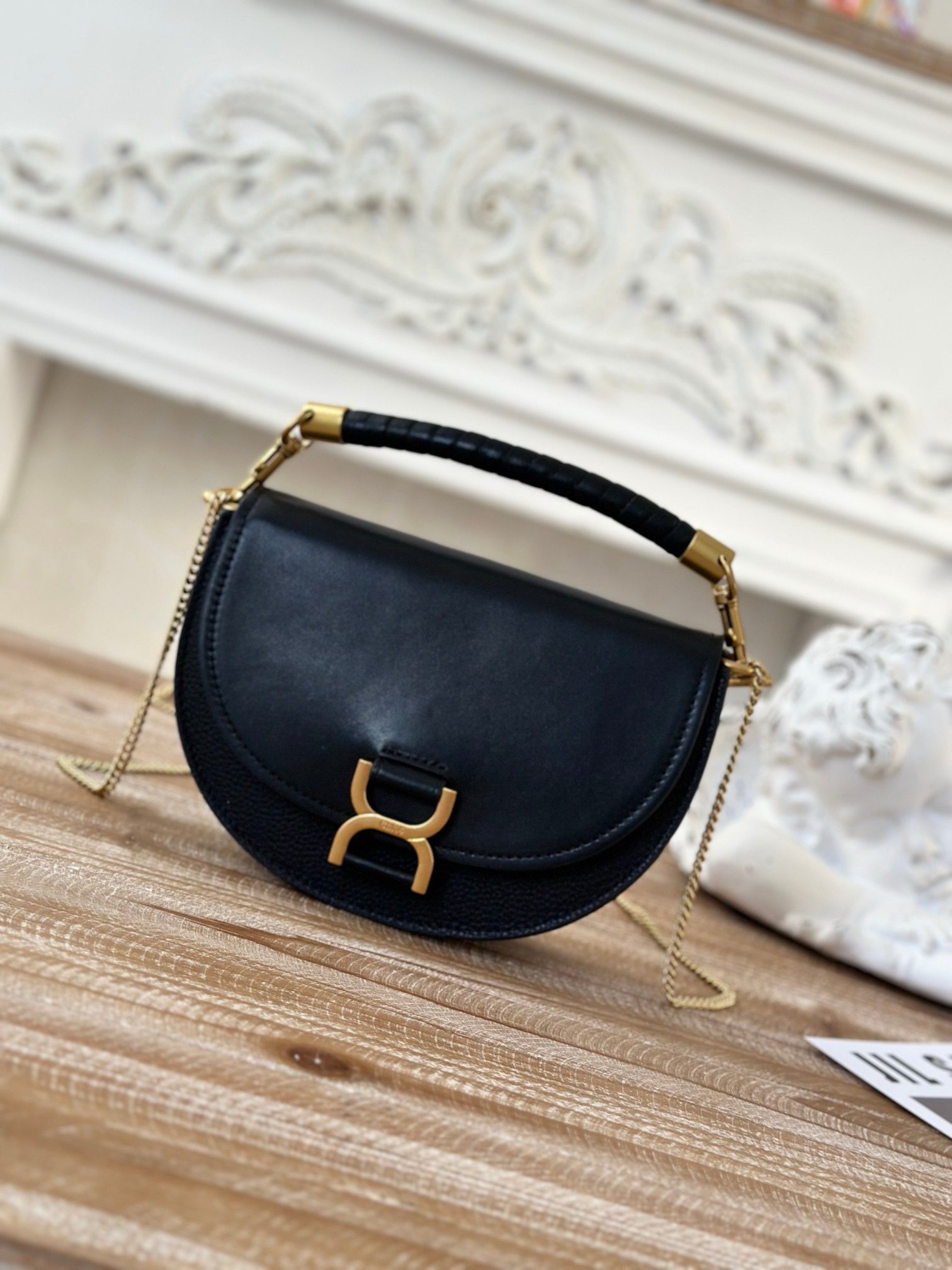 Marcie Chain Flap Bag. Authentic quality luxury bag crafted in genuine leather comes with authenticity card, dust bag and gift bag. Elevating Iconic Elegance: Marcie Line Redefined. Experience a fresh take on *loé's iconic Marcie line with this exquisite chain flap bag, meticulously crafted from a captivating blend of nappa lambskin, grained calfskin, and sumptuous suede. The line's signature hardware undergoes a graceful transformation, now adorned with *loé's engraved jewelry hallmark, adorning the flap with sophistication. An intricately hand-braided top handle pays homage to another hallmark Marcie feature, while a gracefully extended chain strap adds a refined touch. Whether you choose to drape it over your shoulder or wear it cross-body during the day, or opt to detach the strap and carry it by hand for a sophisticated evening ensemble, this flap bag is a versatile masterpiece. *loé's Marcie bag line effortlessly melds a feminine aesthetic with the free-spirited vibe of the '70s. An equestrian-inspired allure takes center stage, elevated by the allure of gleaming gold-toned hardware, resulting in a distinctly feminine yet timelessly chic look.