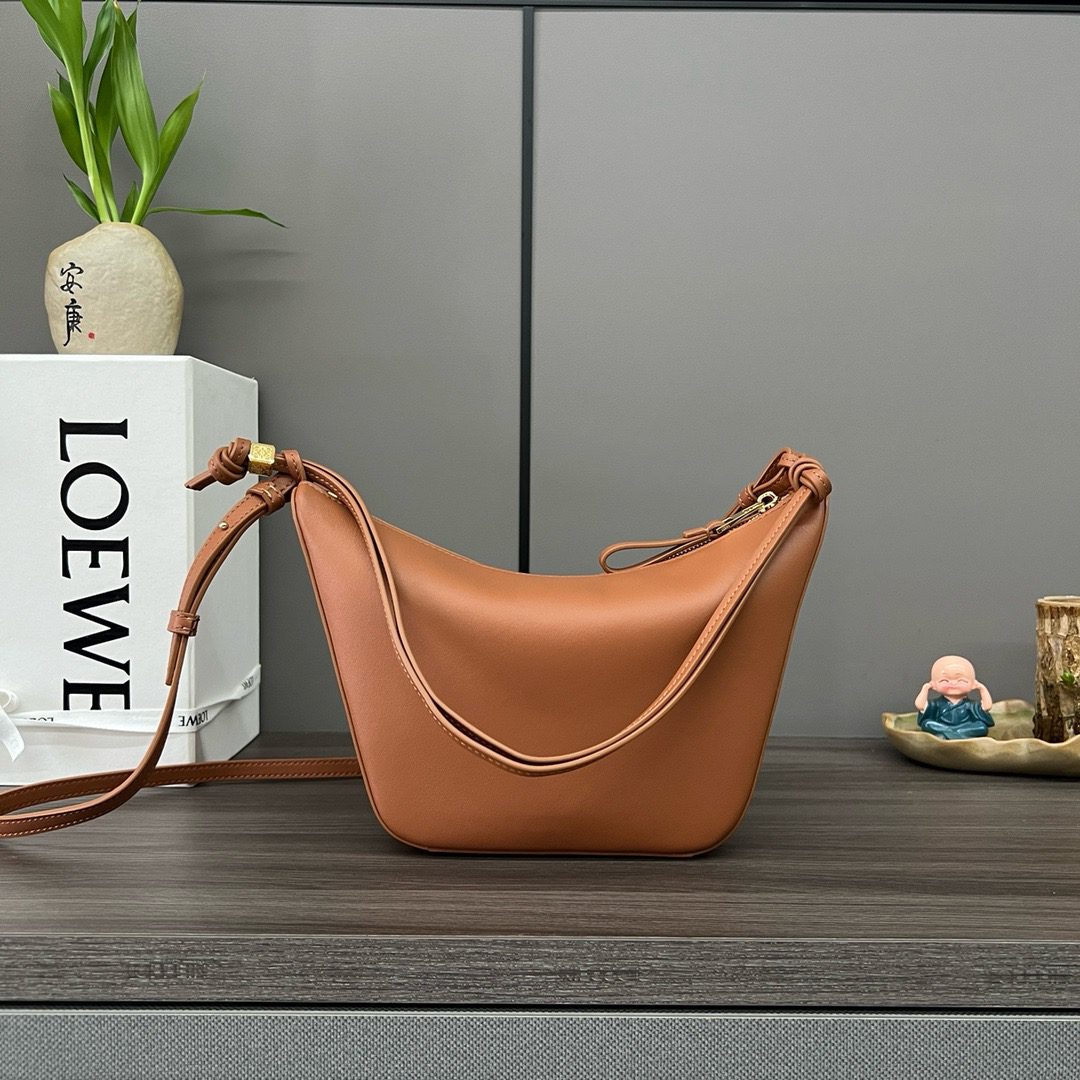 The Mini Hammock Hobo is a contemporary reimagining of *oewe’s iconic Hammock bag. This streamlined variation offers a sleek, sculptural silhouette designed as a versatile sling bag for modern living. Expertly crafted in classic calfskin, it features soft, supple leather and a compact form that adapts effortlessly to your day. The unique design allows for multiple carry options—wear it crossbody, over the shoulder, or by hand. Elegant yet functional, this mini hobo is perfect for essentials, making it an ideal choice for both daily wear and minimalist style statements.