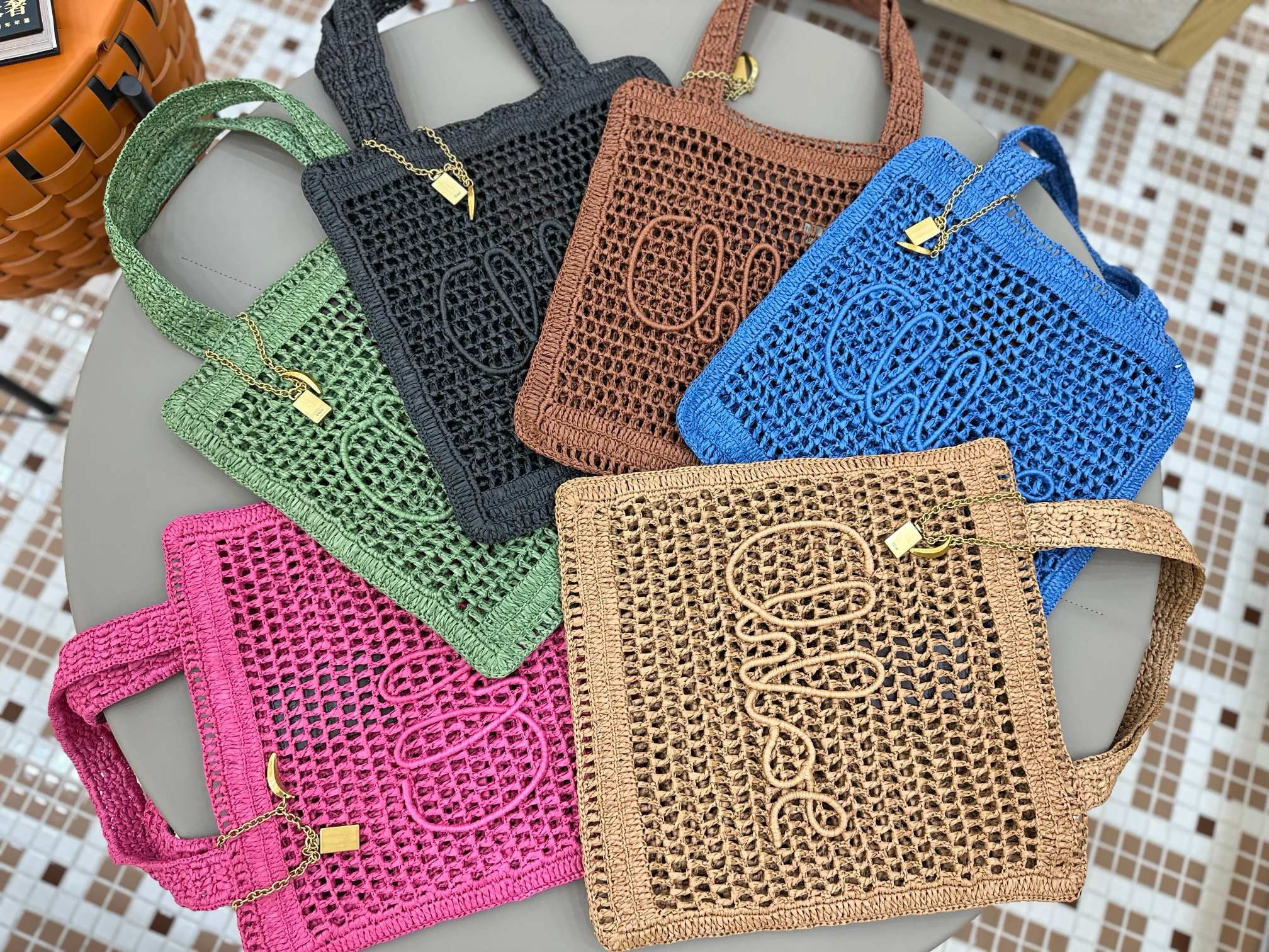 Summer Banana Tote Bag. Authentic quality luxury bag crafted in genuine leather comes with authenticity card, dust bag and gift bag. Heritage in Hand: Where Artisan Craft Meets Summer Elegance. Introducing the Summer Banana Tote—an artisanal masterpiece crafted from raffia and calfskin by a single artisan over 4.5 days in partnership with Made For A Woman. This spacious tote is adorned with a handwritten signature inspired by *loé’s rich heritage, while a playful dangling chain and delicate charms add the perfect finishing touch. A celebration of craftsmanship and effortless summer style.