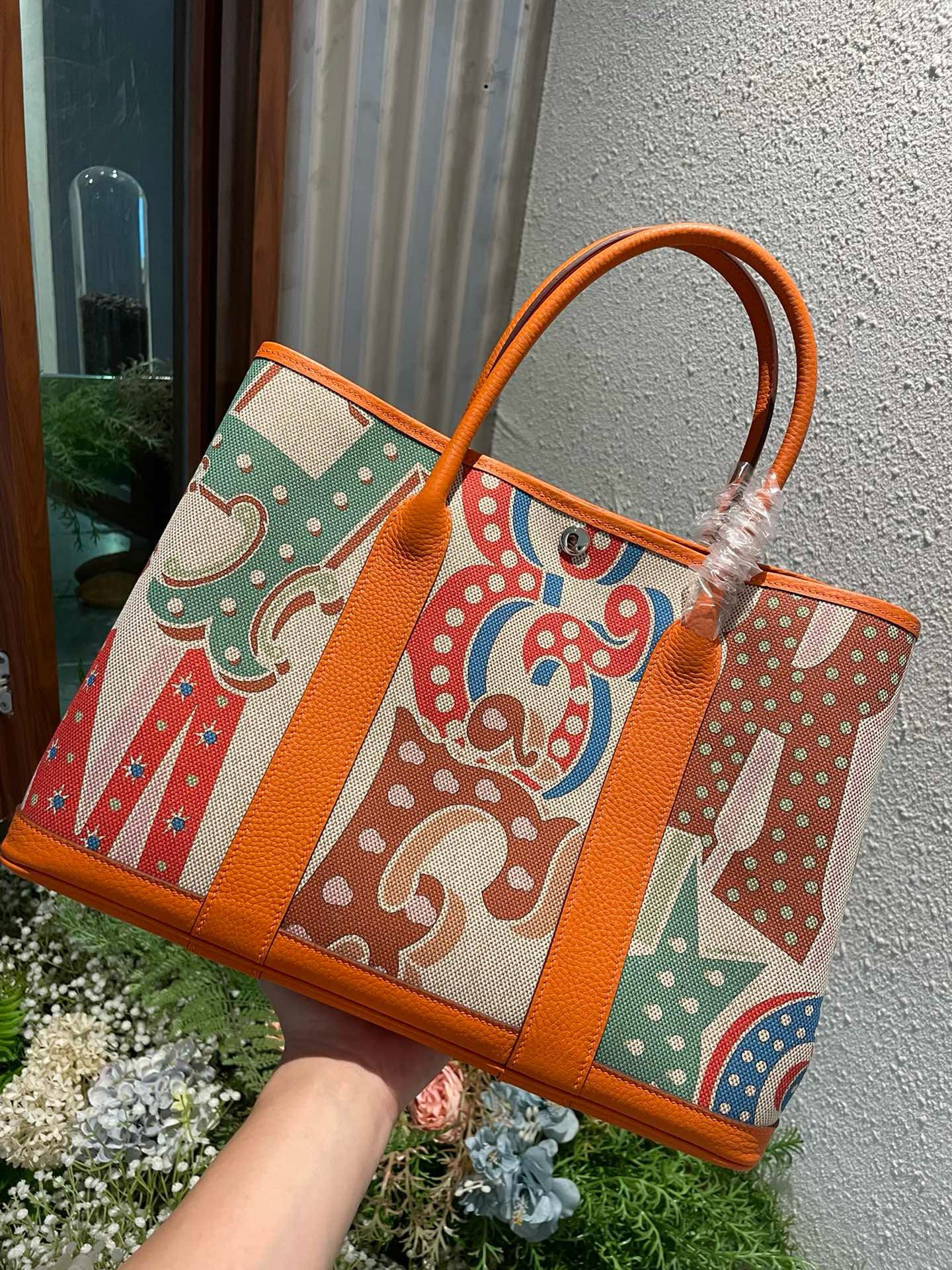 Garden Party Voyage. Authentic quality luxury bag crafted in genuine leather comes with authenticity card, dust bag and gift bag. The Art of Everyday Escape. Chic, structured, and effortlessly refined, the *RMÈS Garden Party Voyage is the perfect companion for your daily adventures or spontaneous weekend getaways. Crafted with precision in supple Negonda leather or canvas with leather trim, this midsize tote strikes the perfect balance between luxury and functionality. Its minimalist silhouette is elevated by discreet Clou de Selle snap closures and expandable sides, offering both form and flexibility. Spacious enough for your essentials yet compact enough to carry with ease, it’s a timeless piece designed to move with you—gracefully. Whether carried in hand or worn over the shoulder, the Garden Party Voyage 36 speaks in whispers of elegance and unmistakable *RMÈS craftsmanship. Every day is a journey. Travel beautifully.