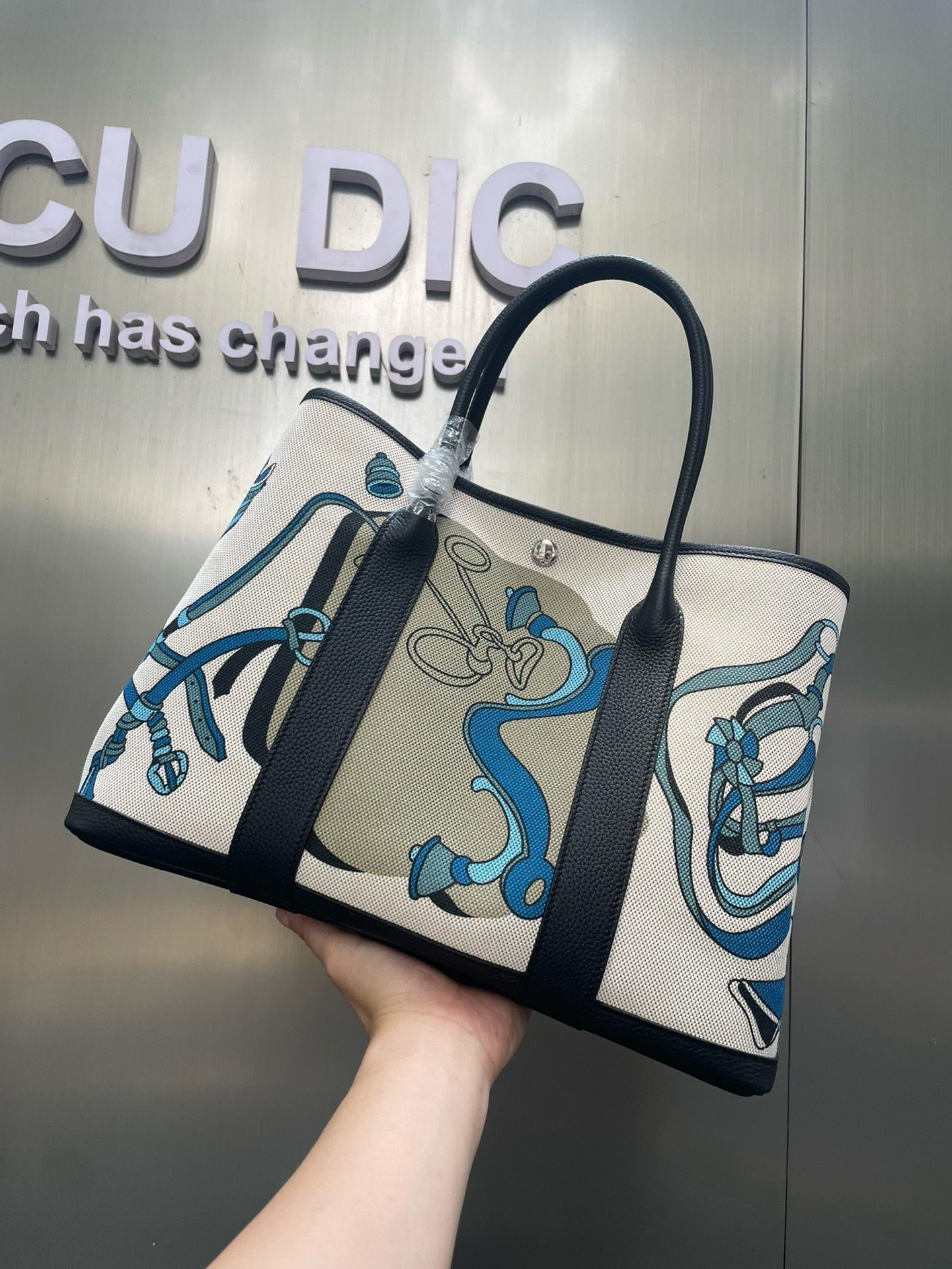 Garden Party Voyage. Authentic quality luxury bag crafted in genuine leather comes with authenticity card, dust bag and gift bag. The Art of Everyday Escape. Chic, structured, and effortlessly refined, the *RMÈS Garden Party Voyage is the perfect companion for your daily adventures or spontaneous weekend getaways. Crafted with precision in supple Negonda leather or canvas with leather trim, this midsize tote strikes the perfect balance between luxury and functionality. Its minimalist silhouette is elevated by discreet Clou de Selle snap closures and expandable sides, offering both form and flexibility. Spacious enough for your essentials yet compact enough to carry with ease, it’s a timeless piece designed to move with you—gracefully. Whether carried in hand or worn over the shoulder, the Garden Party Voyage 36 speaks in whispers of elegance and unmistakable *RMÈS craftsmanship. Every day is a journey. Travel beautifully.