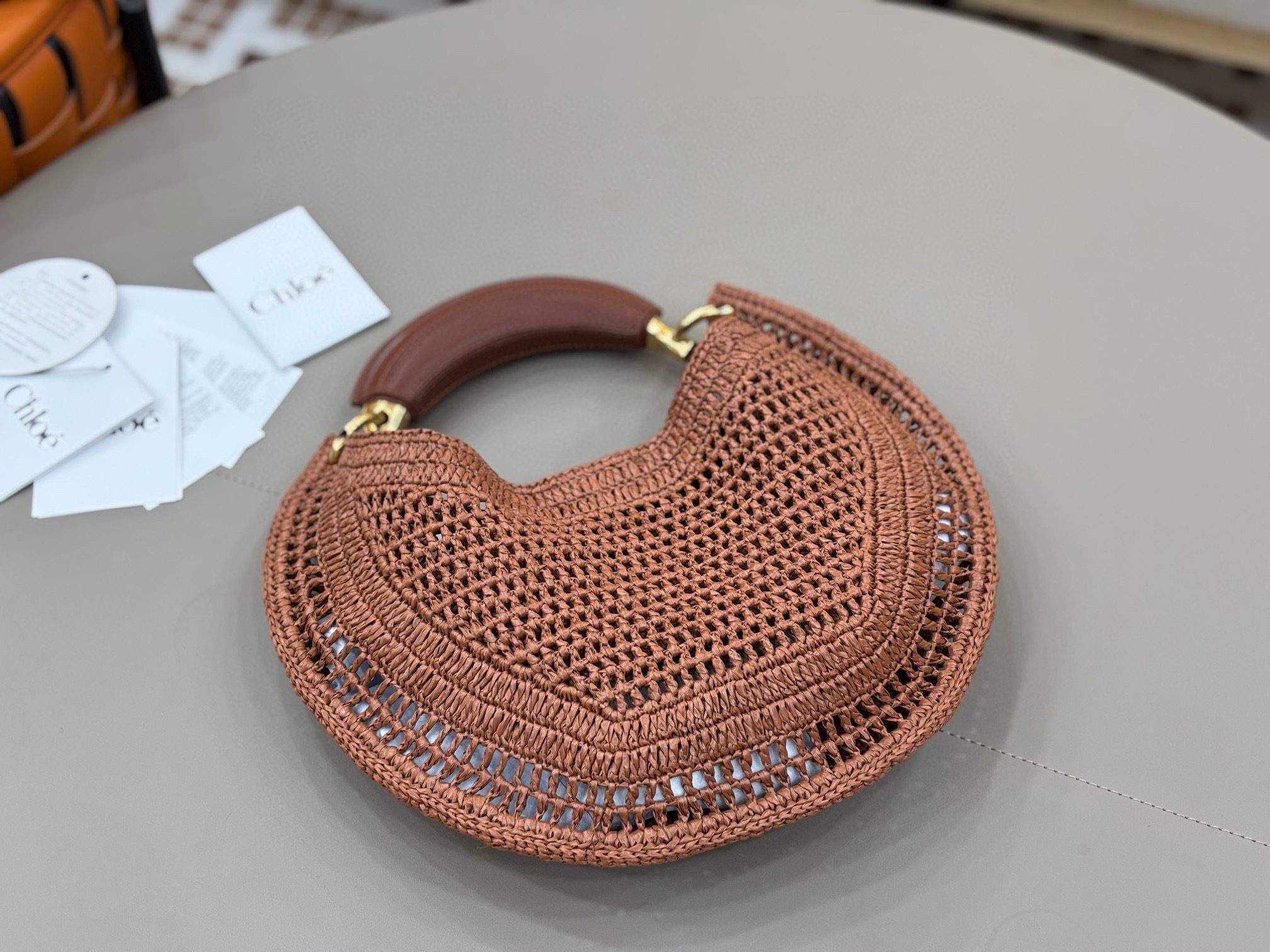 Summer Banana Hobo. Authentic quality luxury bag crafted in genuine leather comes with authenticity card, dust bag and gift bag. Artisanal Spirit, Curved in Style. Say hello to sunshine in bag form. The *LOÉ Summer Banana Hobo Bag is a joyful blend of craftsmanship and creativity, handwoven over four days by a single artisan in collaboration with Made For A Woman. This is not just a bag—it’s a story stitched in raffia and trimmed in luxurious calfskin. Its curved, banana-inspired silhouette hugs the shoulder with ease, while the sculptural handle and handwritten signature nod to *loé’s heritage of effortless elegance. Light, natural, and undeniably chic, it's the perfect companion for sun-soaked escapes or city strolls with a coastal state of mind. A celebration of craftsmanship, femininity, and the art of slow fashion.