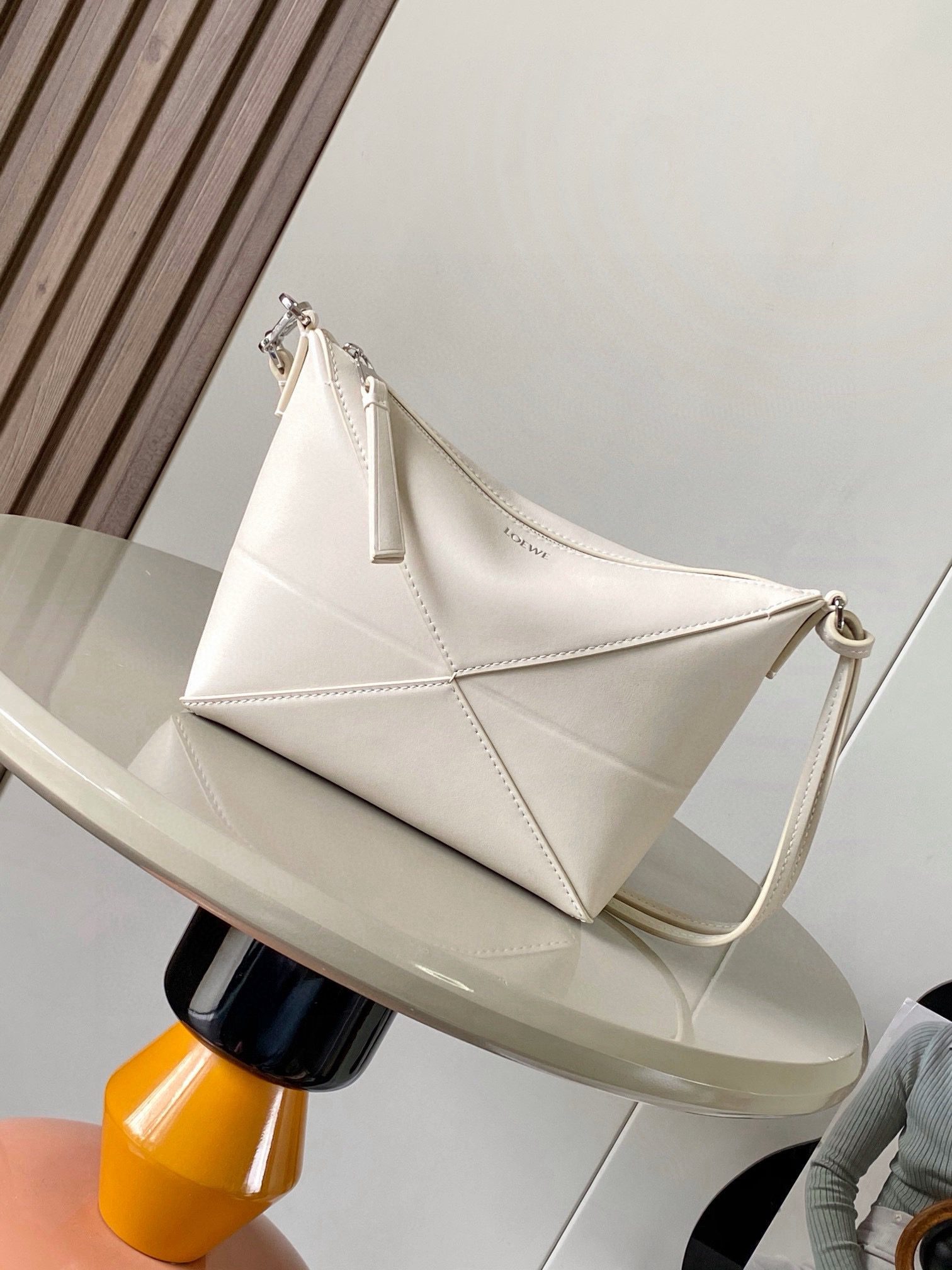 Puzzle Fold Pouch. Authentic quality luxury bag crafted in genuine leather comes with authenticity card, dust bag and gift bag. Sculpted Sophistication — The Art of Function. The Puzzle Fold Pouch redefines modern elegance with its sculptural geometry and effortless versatility. Crafted in luxurious shiny nappa calfskin, its signature folded panels create a dynamic, architectural silhouette that’s instantly recognizable. Both stylish and practical, this pouch transitions seamlessly from day to night—perfect for carrying essentials with a touch of *OEWE sophistication. A masterpiece of craftsmanship, it’s the ultimate blend of innovation and timeless design.