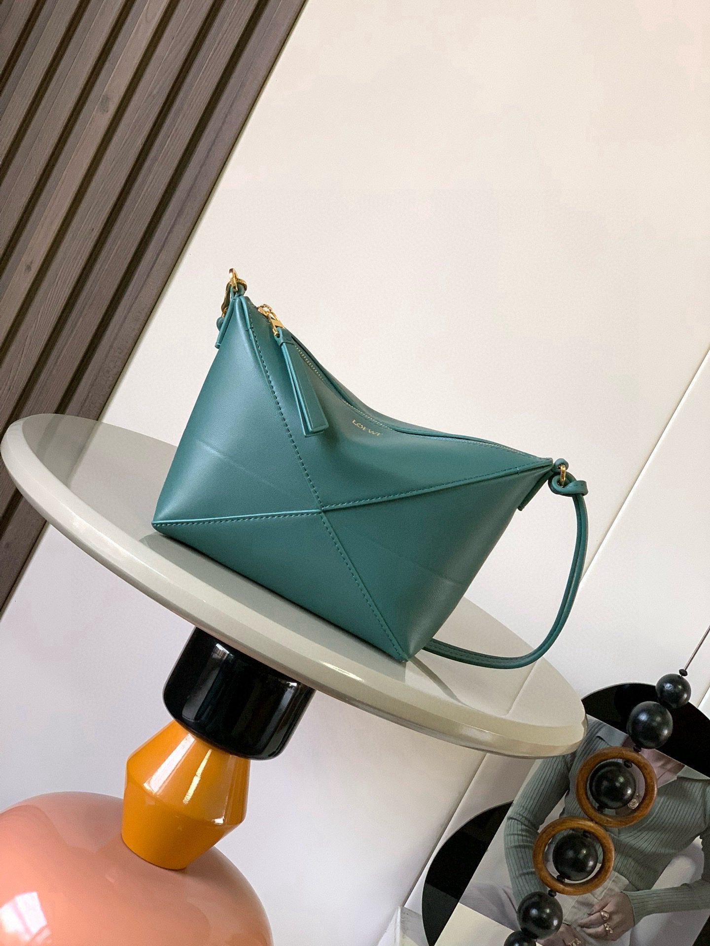 Puzzle Fold Pouch. Authentic quality luxury bag crafted in genuine leather comes with authenticity card, dust bag and gift bag. Sculpted Sophistication — The Art of Function. The Puzzle Fold Pouch redefines modern elegance with its sculptural geometry and effortless versatility. Crafted in luxurious shiny nappa calfskin, its signature folded panels create a dynamic, architectural silhouette that’s instantly recognizable. Both stylish and practical, this pouch transitions seamlessly from day to night—perfect for carrying essentials with a touch of *OEWE sophistication. A masterpiece of craftsmanship, it’s the ultimate blend of innovation and timeless design.