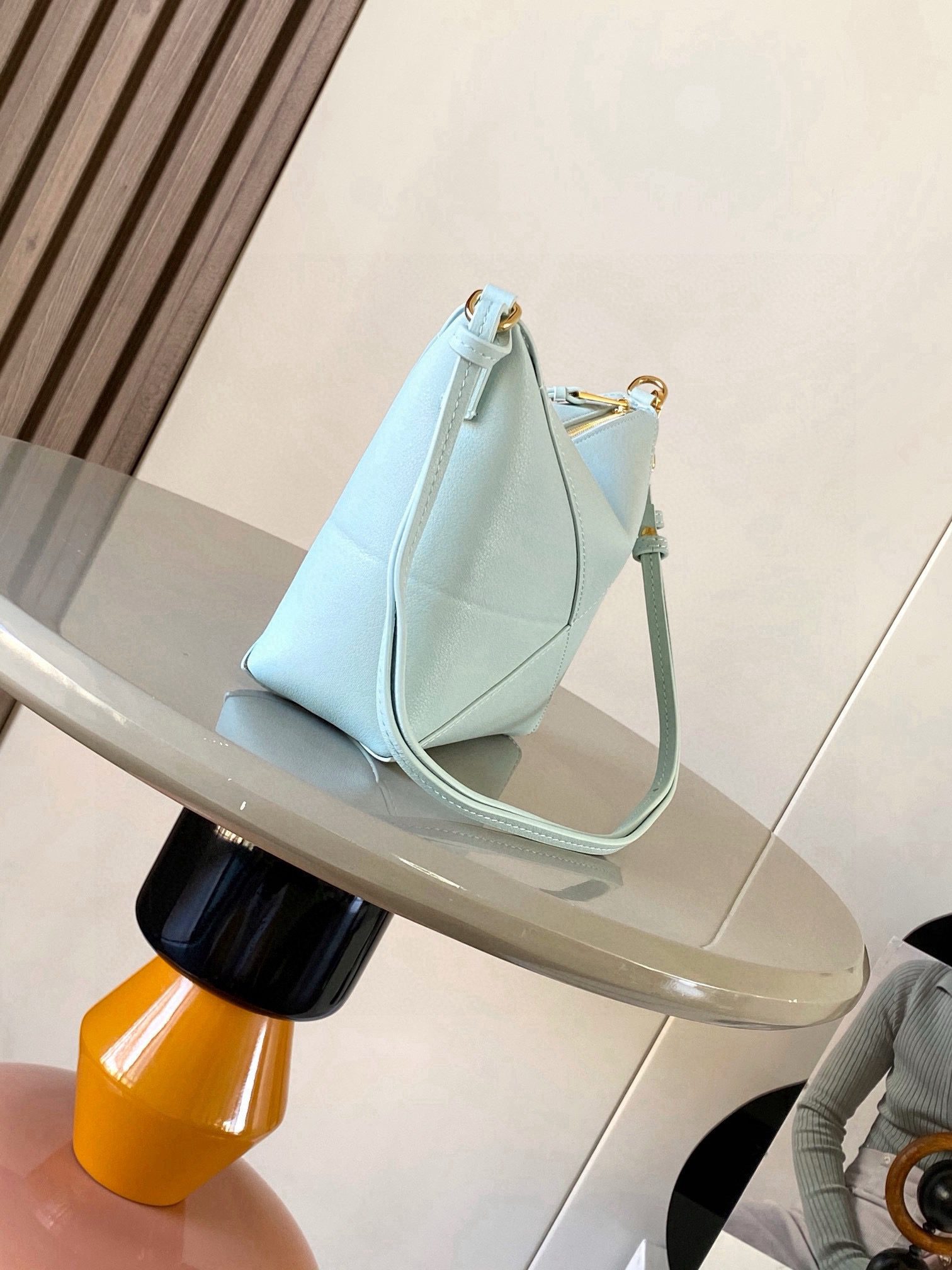 Puzzle Fold Pouch. Authentic quality luxury bag crafted in genuine leather comes with authenticity card, dust bag and gift bag. Sculpted Sophistication — The Art of Function. The Puzzle Fold Pouch redefines modern elegance with its sculptural geometry and effortless versatility. Crafted in luxurious shiny nappa calfskin, its signature folded panels create a dynamic, architectural silhouette that’s instantly recognizable. Both stylish and practical, this pouch transitions seamlessly from day to night—perfect for carrying essentials with a touch of *OEWE sophistication. A masterpiece of craftsmanship, it’s the ultimate blend of innovation and timeless design.